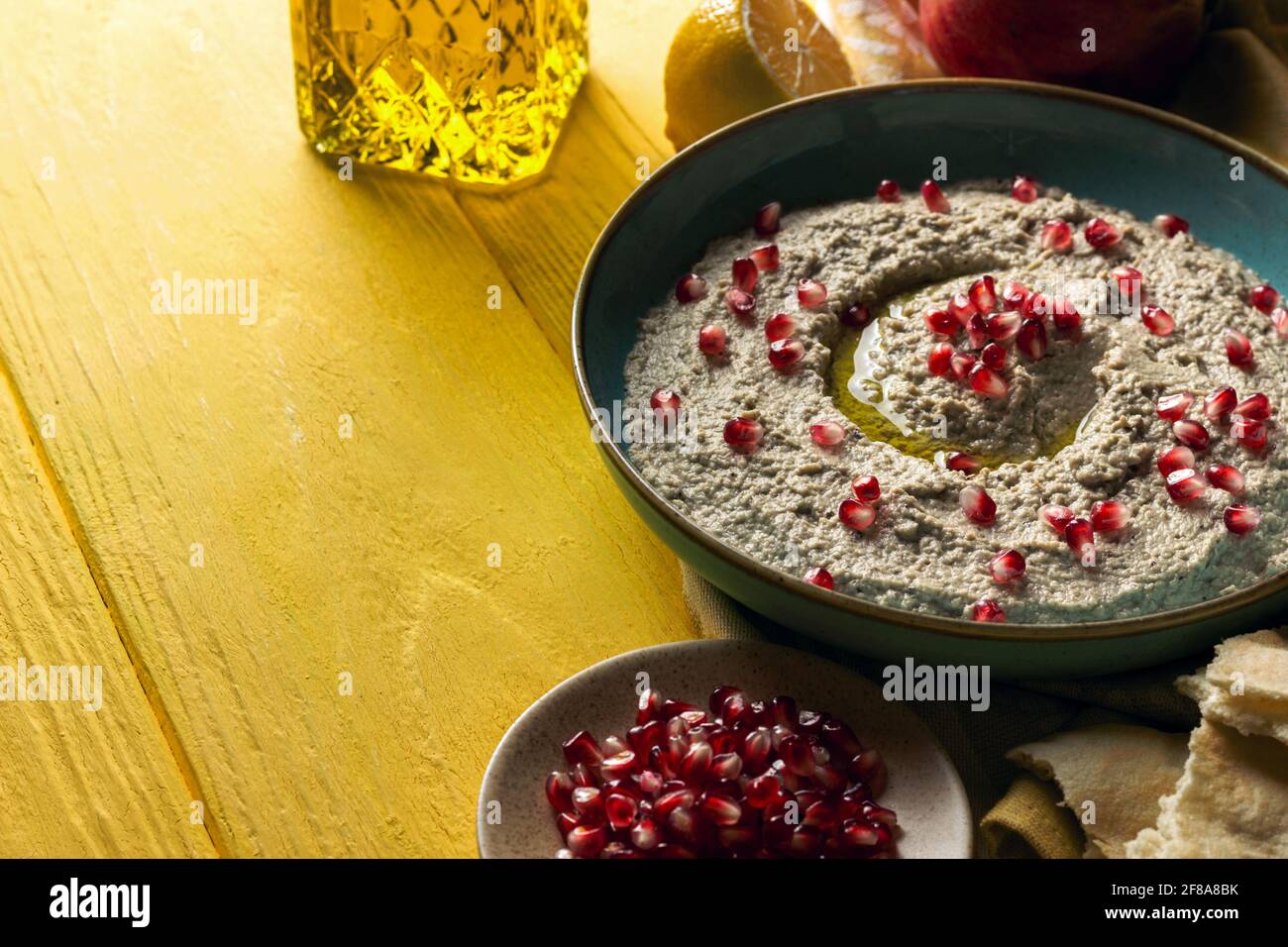Baba ganoush or mutabal, Middle Eastern eggplant dip sauce garnished with pomegranate seeds, with various ingredients and served in a light blue plate Stock Photo