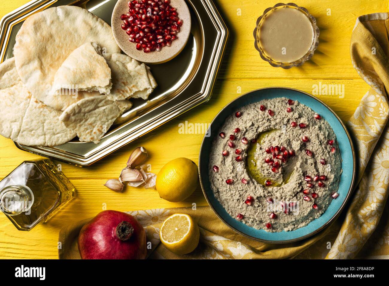 Baba ganoush or mutabal, Middle Eastern eggplant dip sauce garnished with pomegranate seeds, with various ingredients and served in a light blue plate Stock Photo