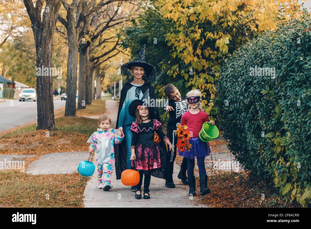 Trick or treat. Mother with children going to trick or treat on Halloween holiday. Mom with kids in party costumes with baskets going to neighbourhood Stock Photo