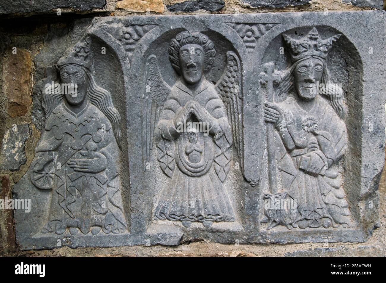 Stone carving of three religious figures on wall of ruins in Ireland Stock Photo