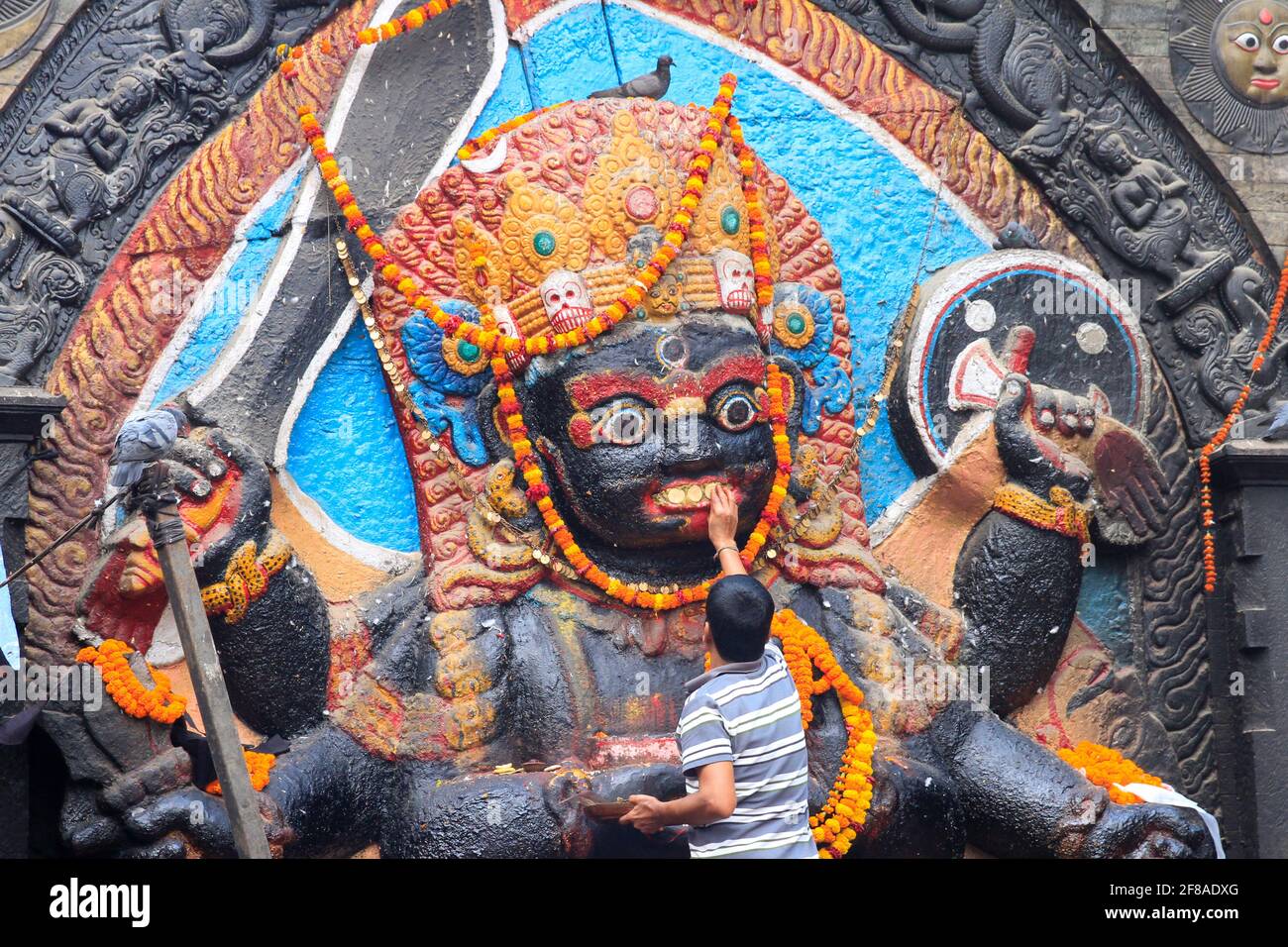 Man painting stone carved god on wall in Kathmandu, Nepal Stock Photo