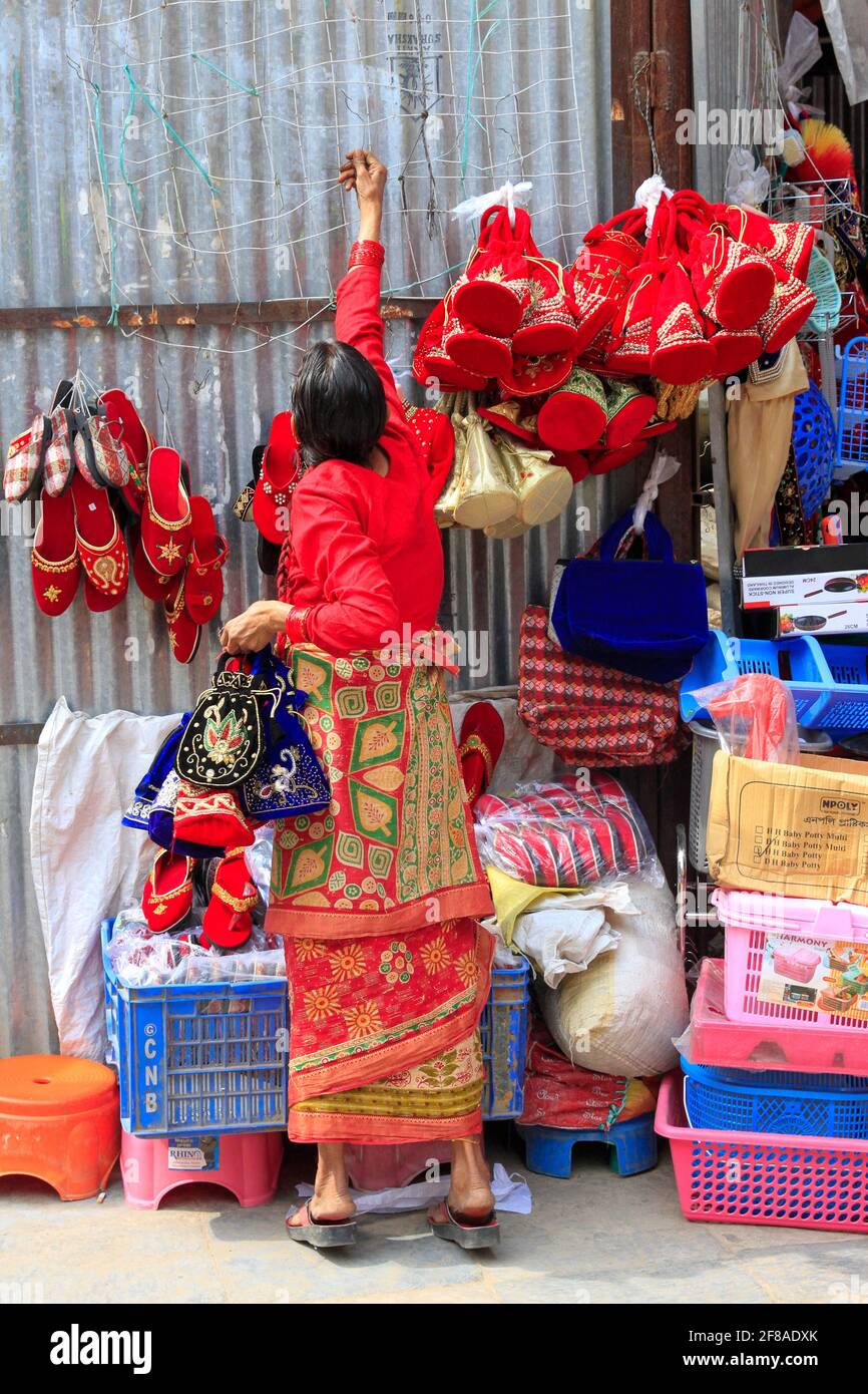 Woman in traditional dress at market hanging items in Kathmandu, Nepal Stock Photo