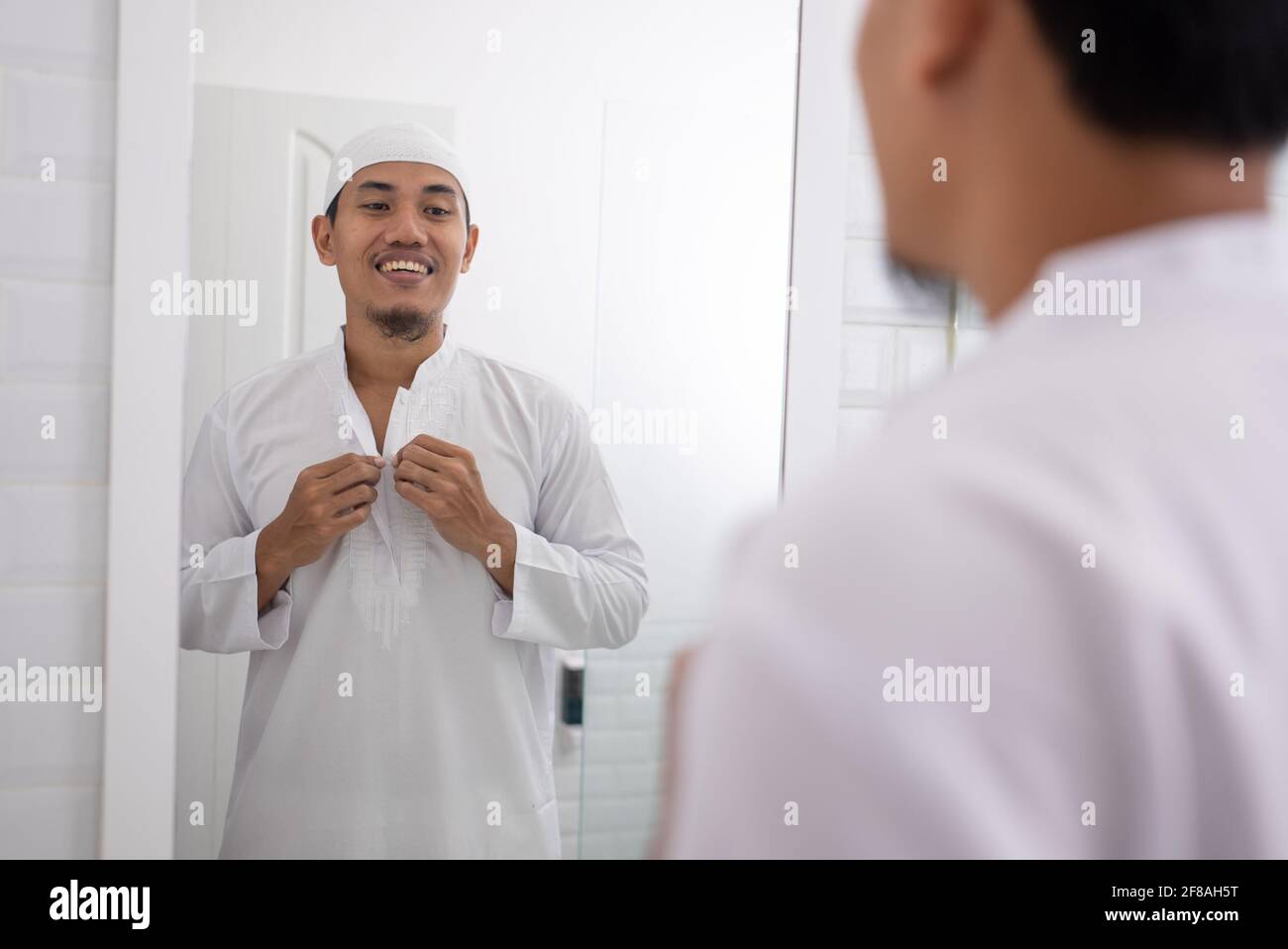 muslim man looking at mirror and get dressed before going to the mosque