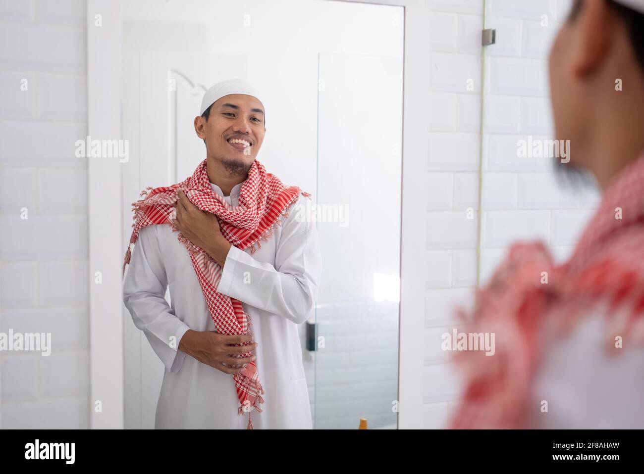 muslim man looking at mirror and get dressed before going to the mosque