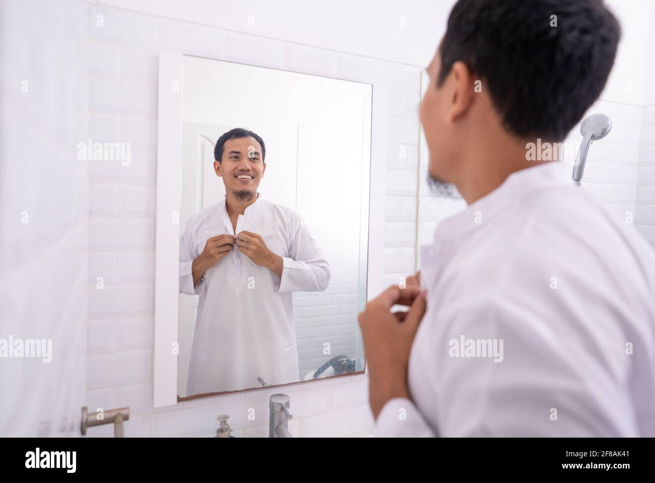 muslim man looking at mirror and get dressed before going to the mosque