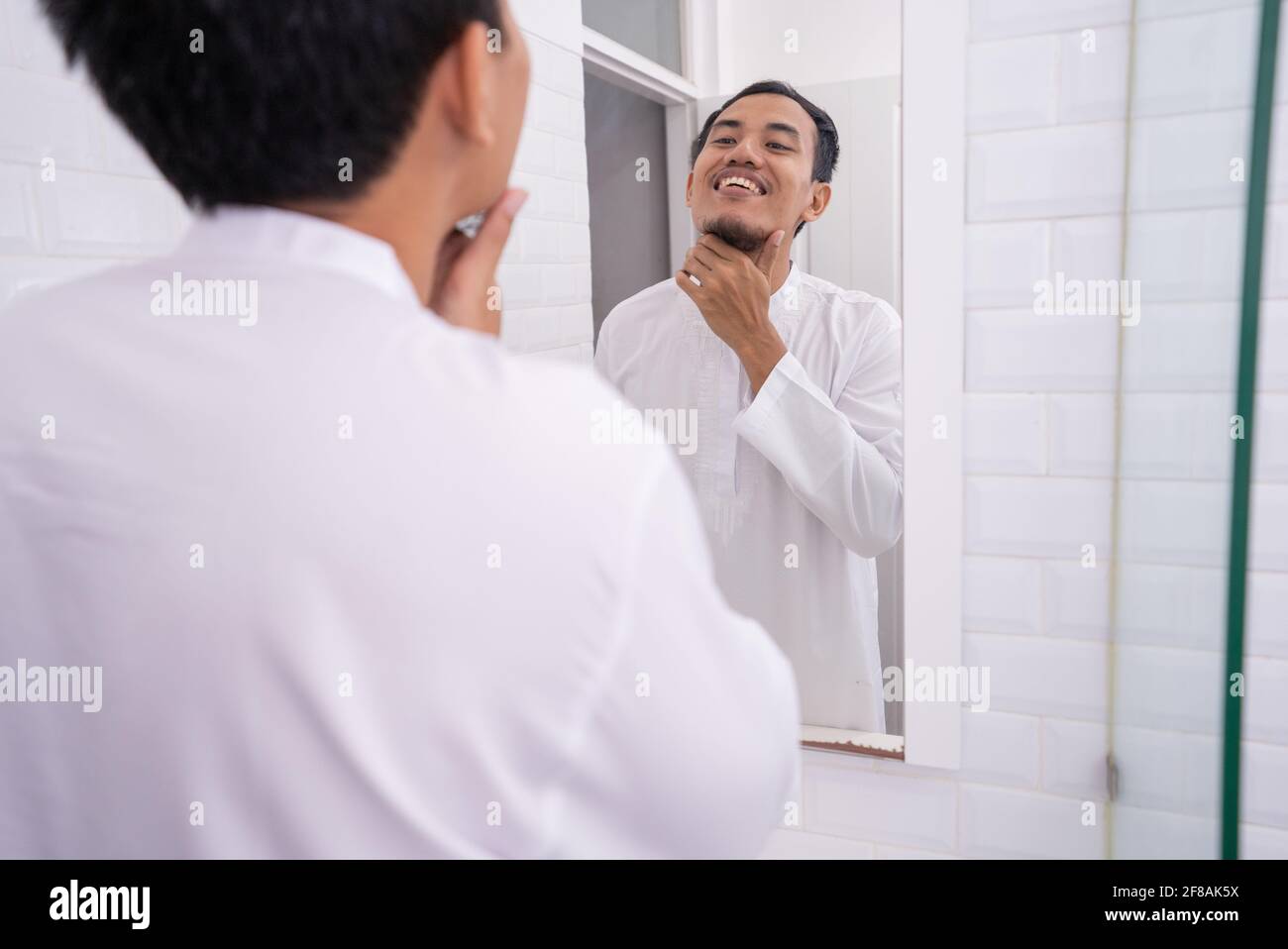 muslim man looking at mirror and get dressed before going to the mosque