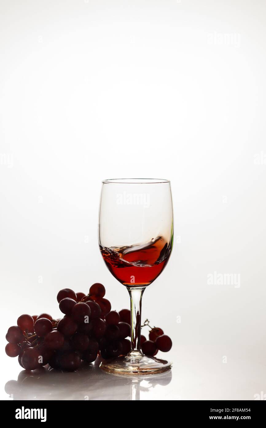 Red wine in glass with red grape. Stock Photo
