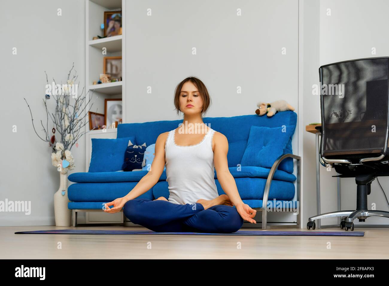Young woman practicing youga at home sitting in easy pose on mat Stock ...
