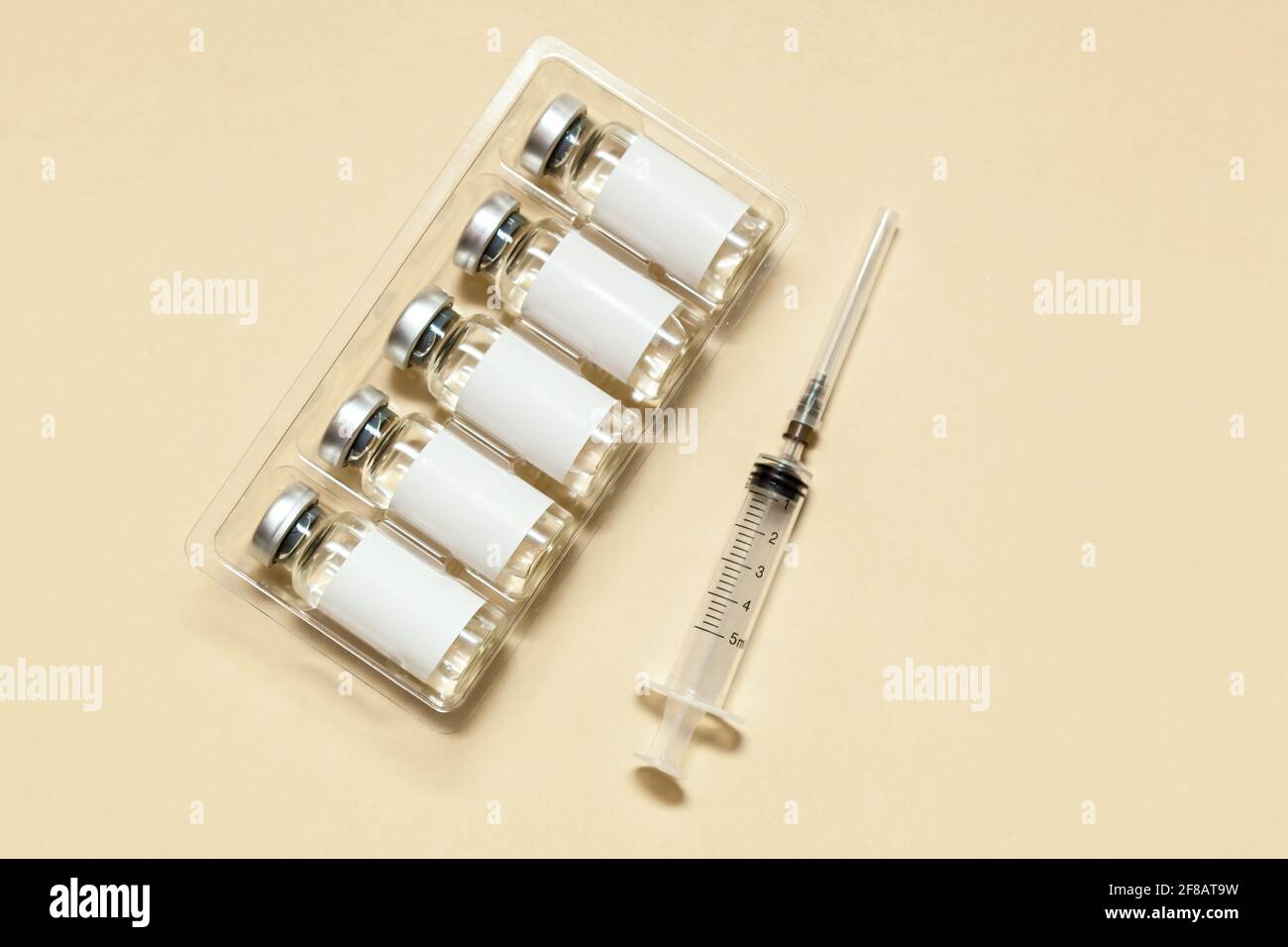 Syringe with vaccine in bubbles and stickers without inscription on a beige background. Medicine concept. Photo with place for your text and design.No Stock Photo