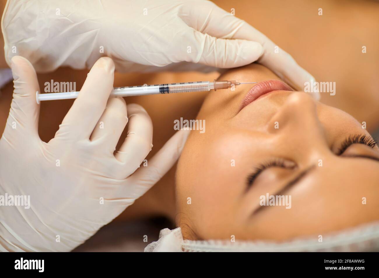 Cosmetologist making botox beauty injection in womans lips with syringe in beauty spa salon Stock Photo