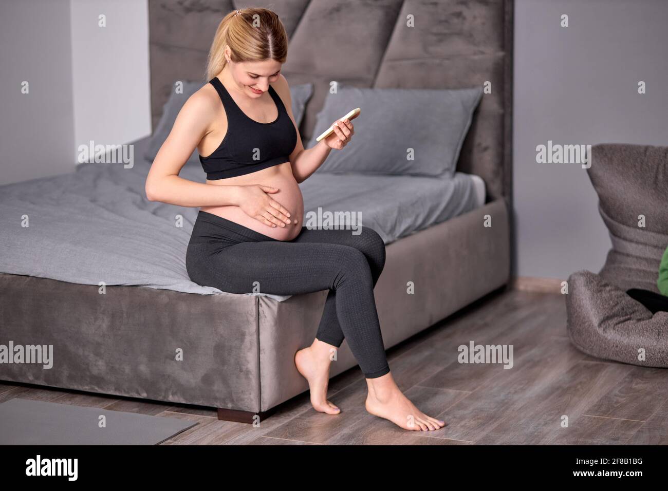 Tummy Rested Side view on beautiful pregnant woman sitting with mobile phone, having ...