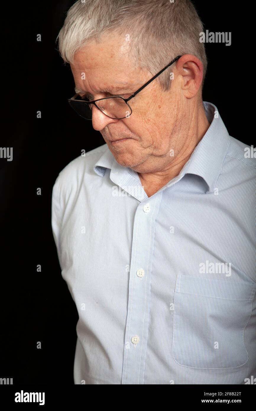 Senior Man Wearing Spectacles Looking Down Stock Photo