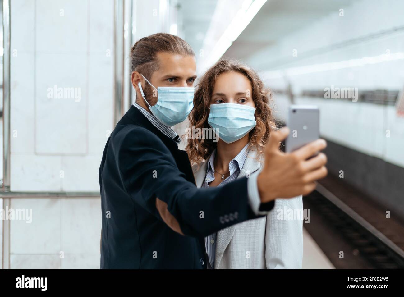 young couple in protective masks taking selfies in subway. Stock Photo