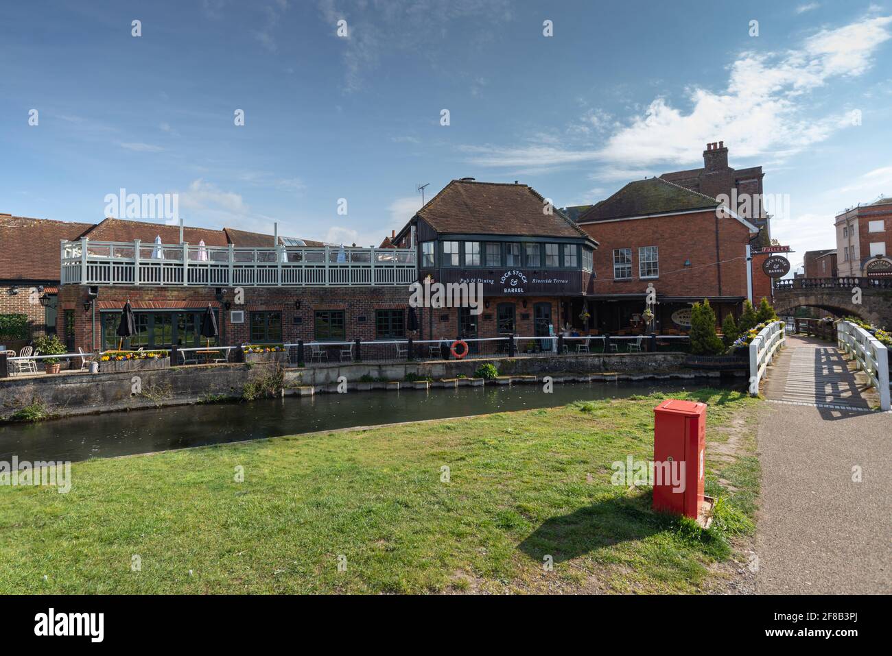 Lock Stock and Barrel Fullers pub riverside terrace at River Kennet with colourful spring flowers and footpath bridge by canal, No people. Stock Photo