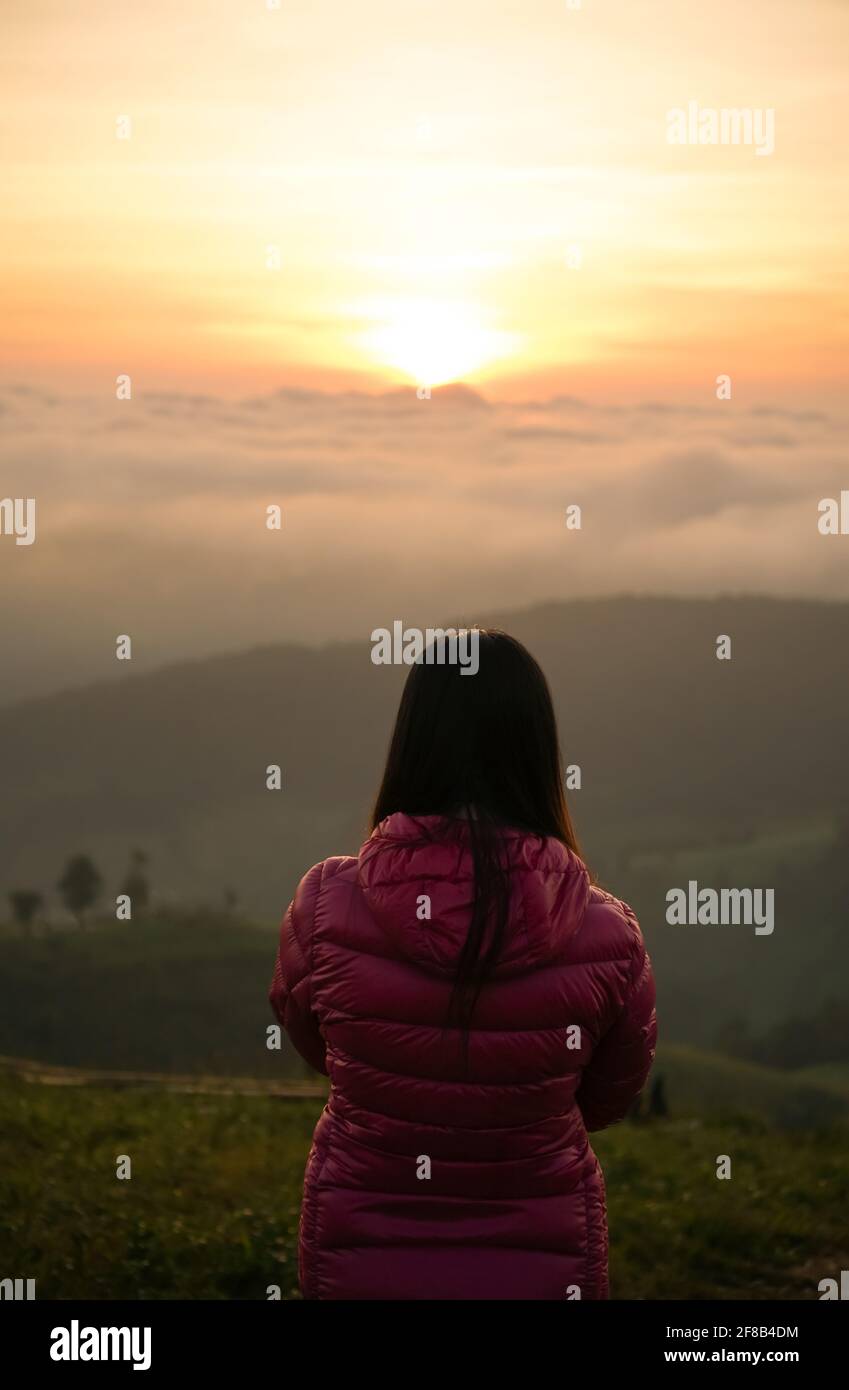 woman watching sunrise alone at hilltop Stock Photo