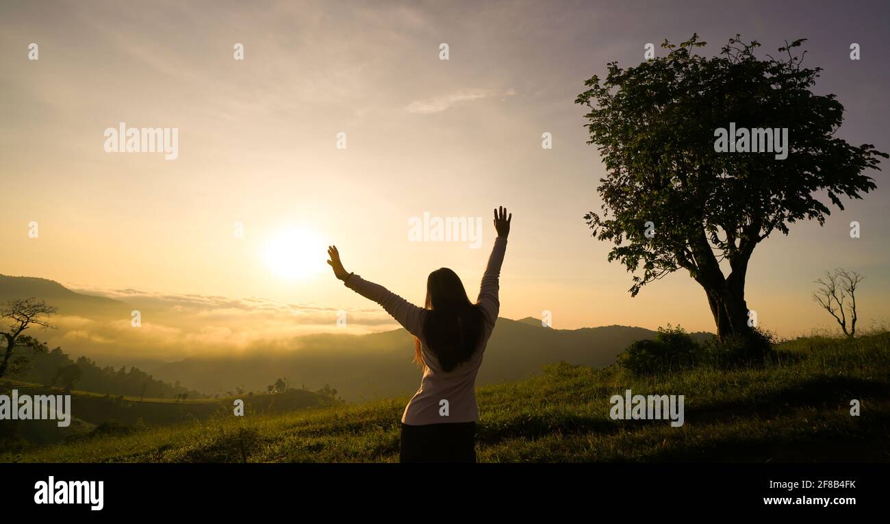 Happy woman enjoying life at sunrise in mountains Stock Photo