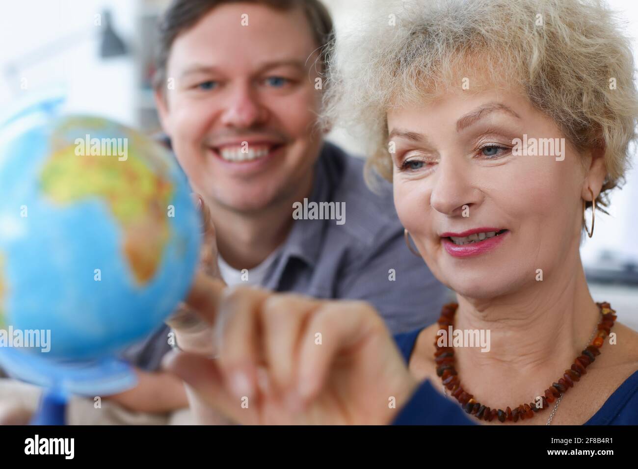Elderly woman with her son is looking at globe Stock Photo