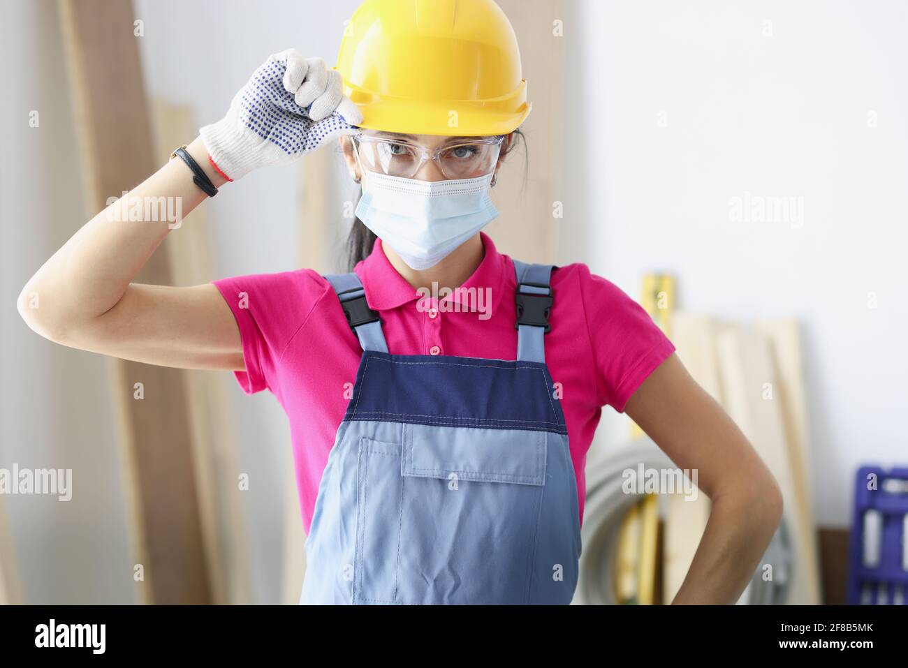 Woman builder in yellow hard hat and protective mask Stock Photo