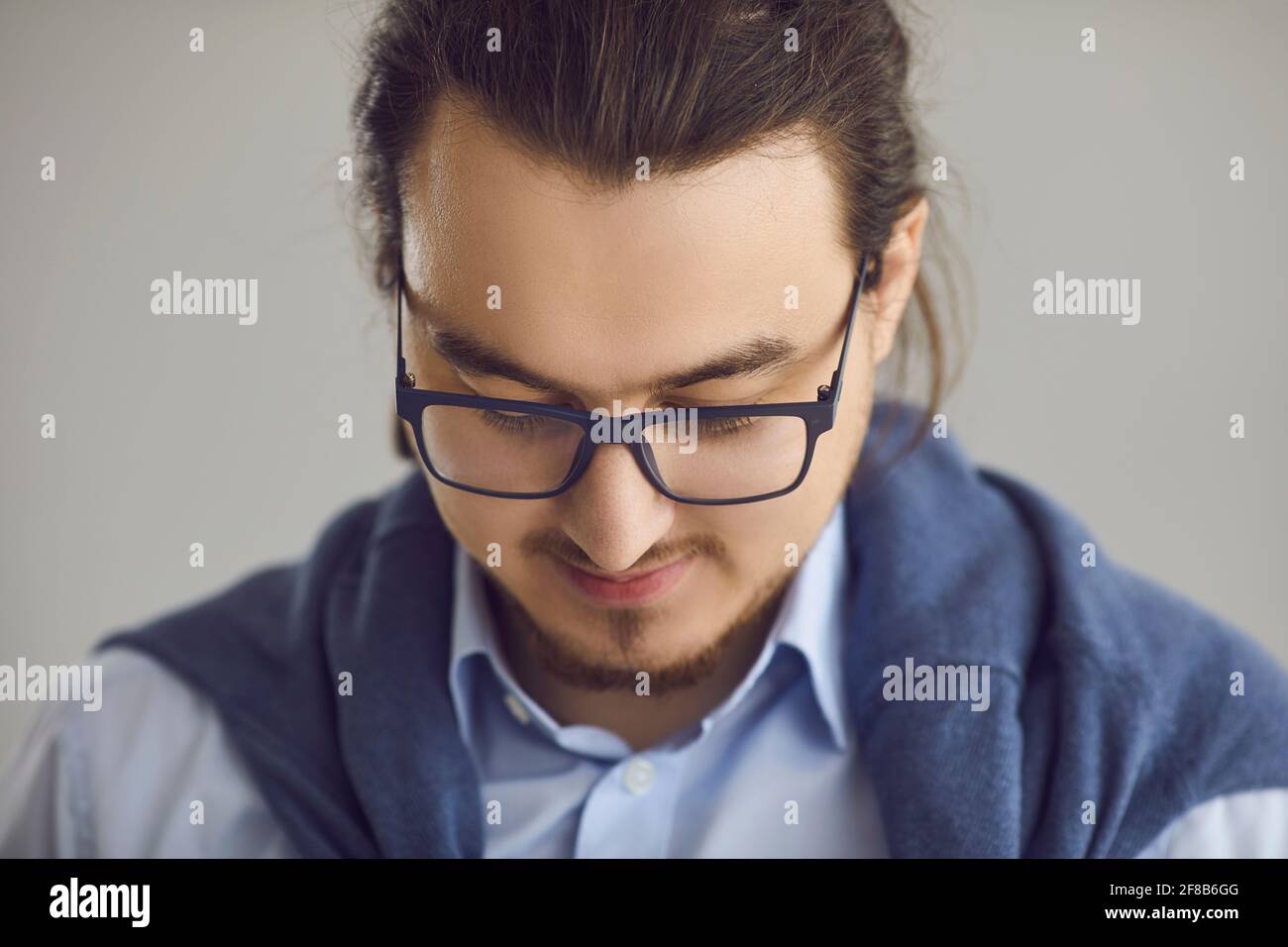 Closeup portrait of smart young man in glasses and shirt on gray studio background Stock Photo