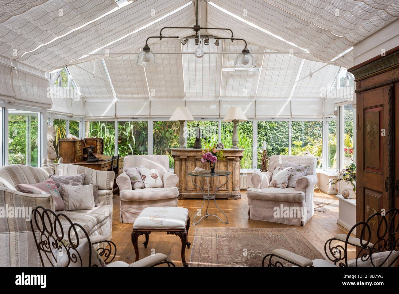 Pair of armchairs and sofa in conservatory extension of 1930s West Sussex coastal home Stock Photo