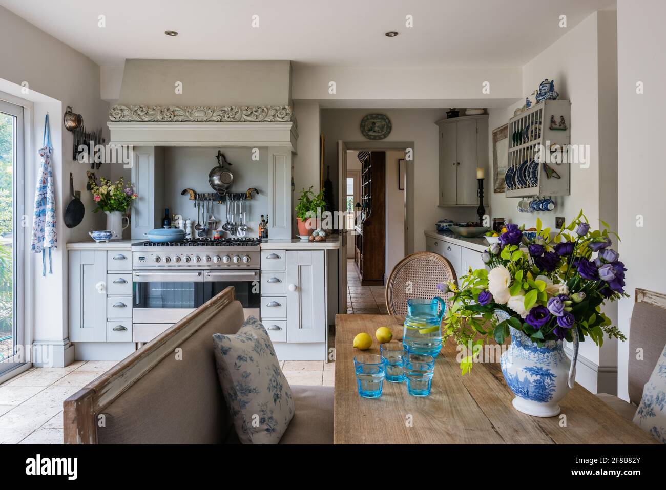 Shaker style kitchen with Gustavian benches and Travertine floor in 1930s West Sussex coastal kitchen redesign. Stock Photo