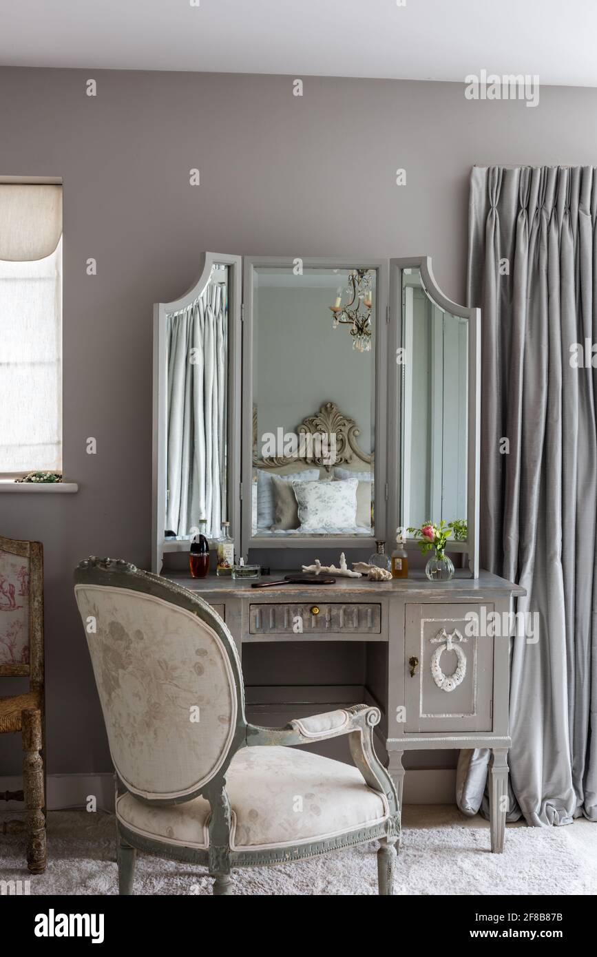 Gustavian dressing table with antique French chair and walls in Lamp Room Grey in bedroom of West Sussex coastal renovation. Stock Photo