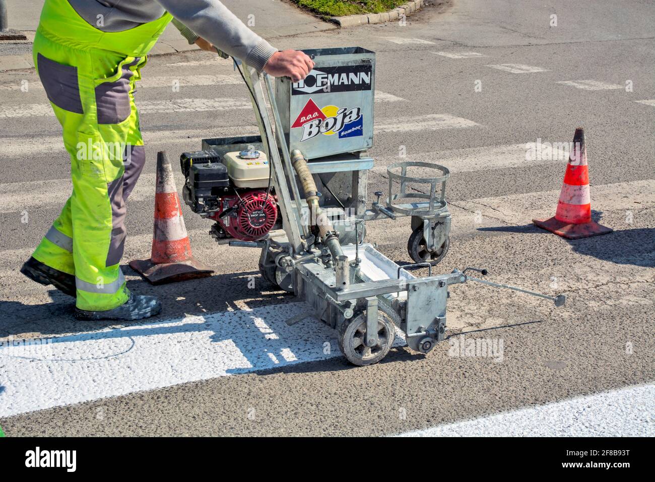 Zrenjanin, Serbia, March 26, 2021. Workers of a company that paints pedestrian crossings, popularly called 'zebras', mark and paint on asphalt. Stock Photo
