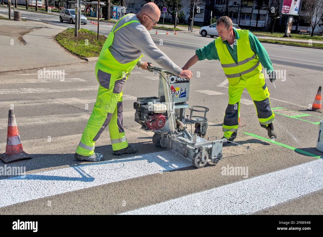Zrenjanin, Serbia March 26, 2021. Workers of a company that paints pedestrian crossings, popularly called 'zebras', mark and paint on asphalt. Stock Photo