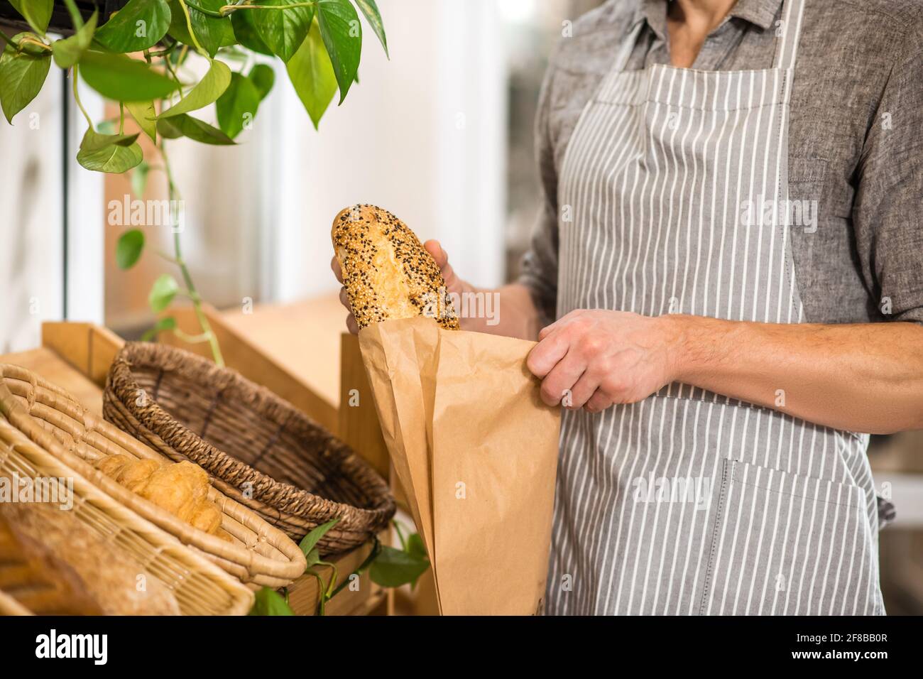 Male hands putting fresh bread in paper packaging Stock Photo