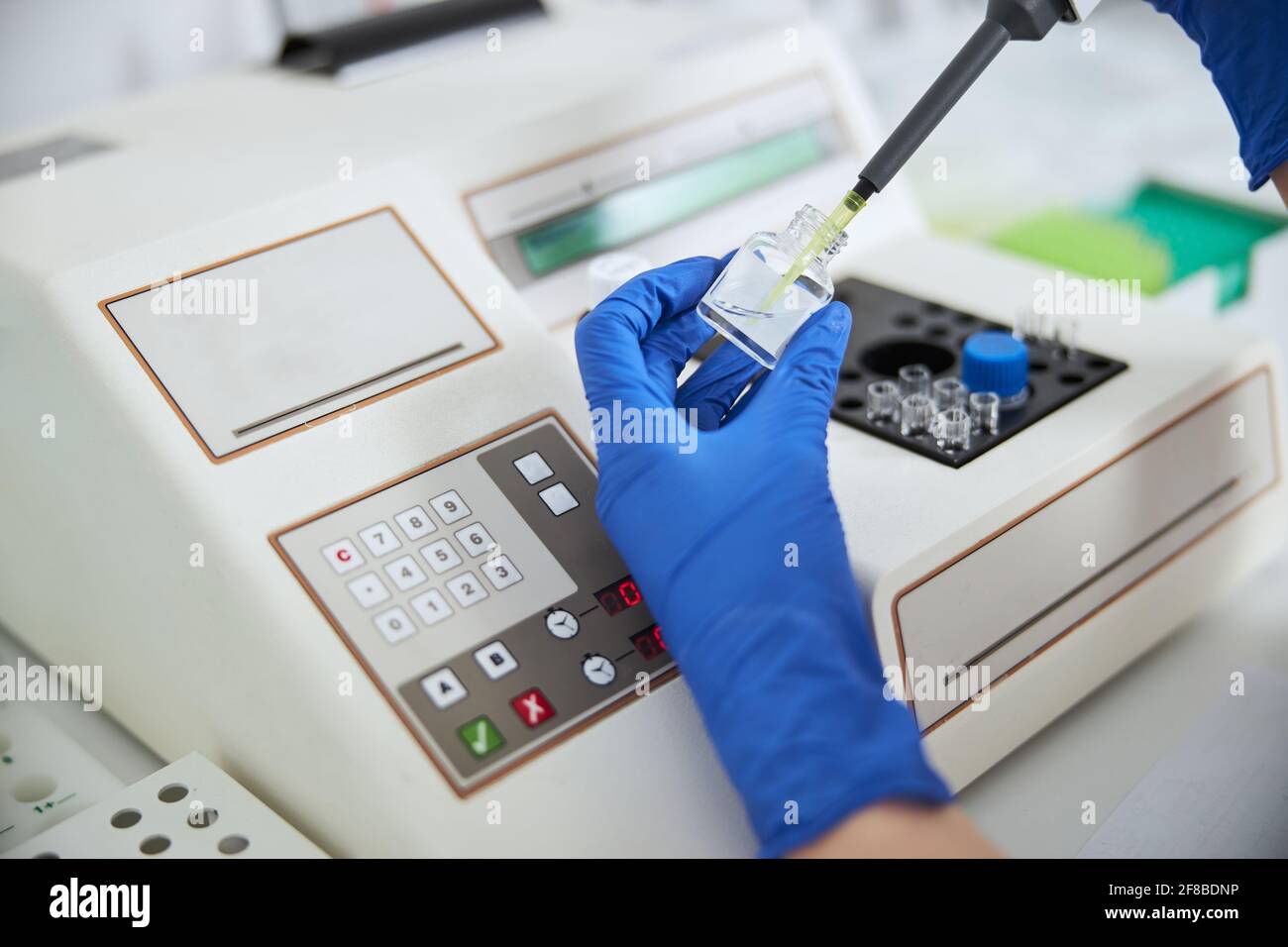 Lab technician in sterile gloves aspirating liquid from a reagent