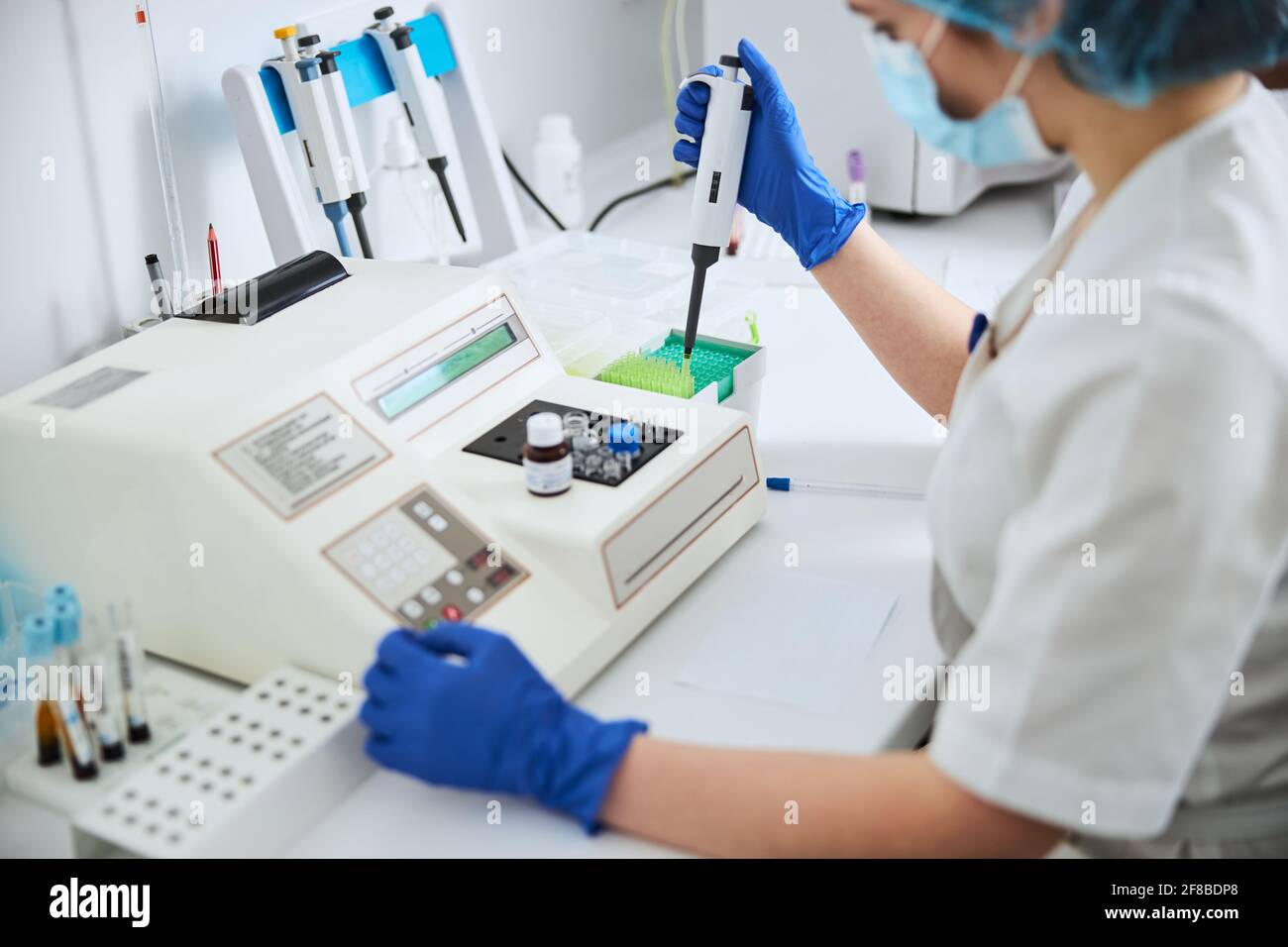Scientist in a mask preparing a laboratory tool for pipetting Stock Photo