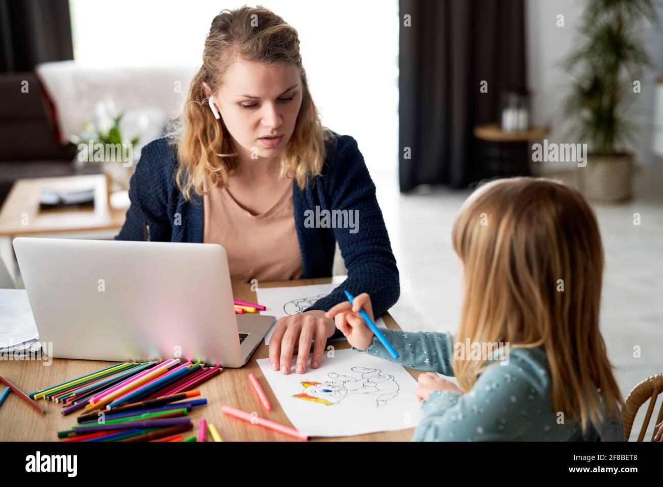 Mother looks after her daughter during home office Stock Photo