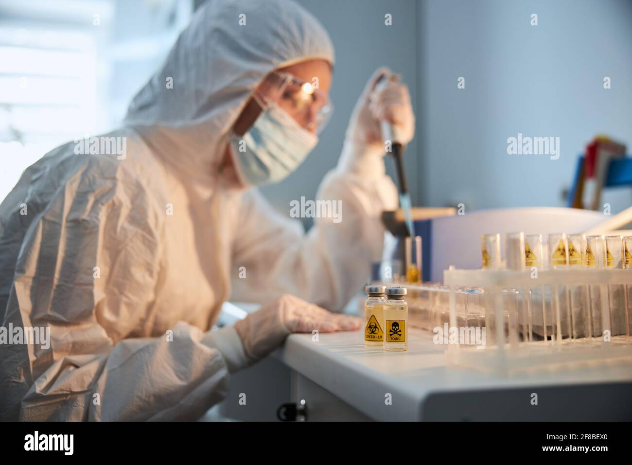 Experienced researcher in a hazmat suit working on a COVID vaccine Stock Photo