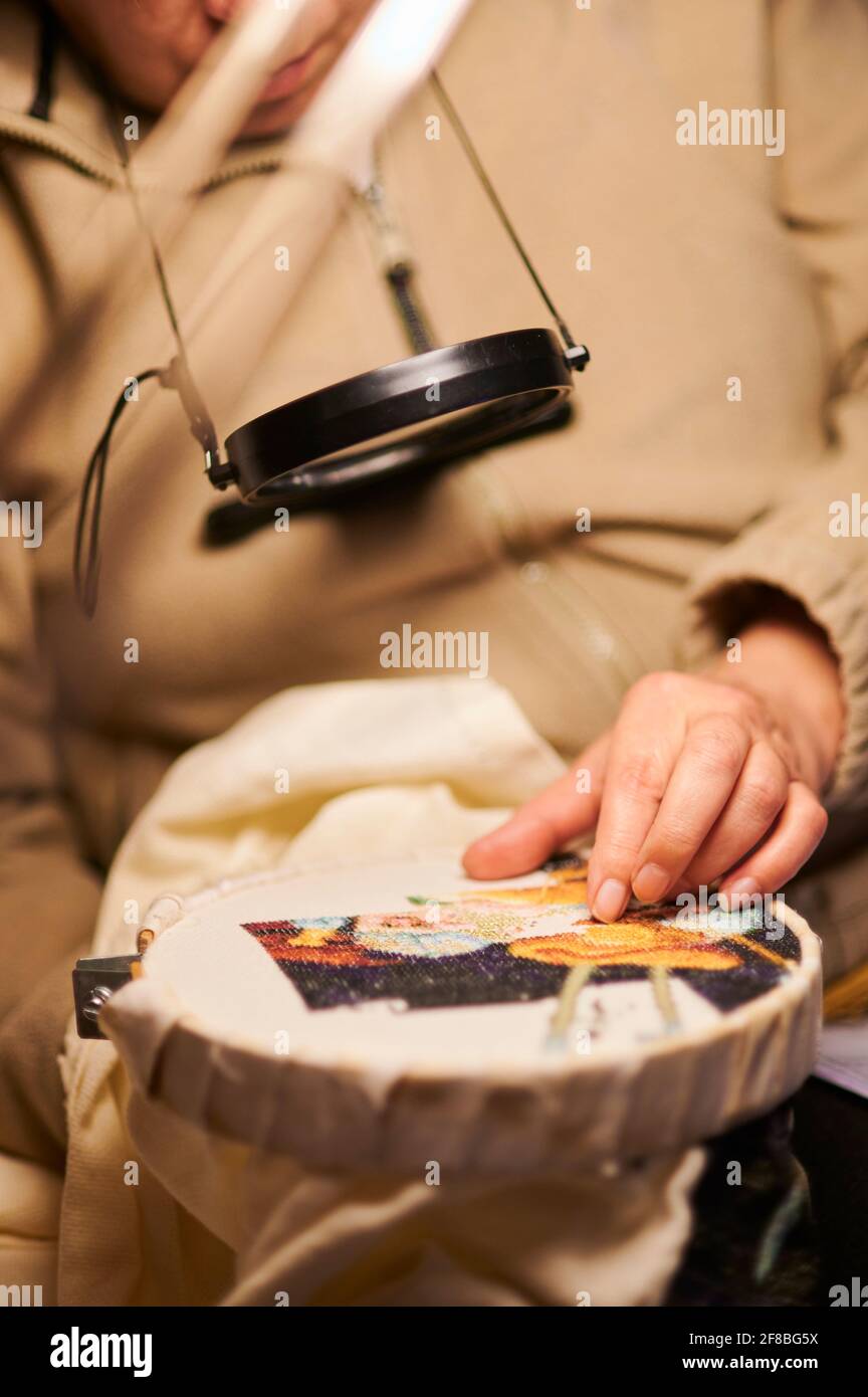 Woman hands doing cross-stitch. A close up of embroidery. Stock Photo