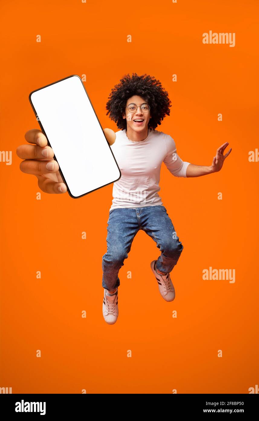 Mobile app advertisement. Excited teen black guy showing smartphone