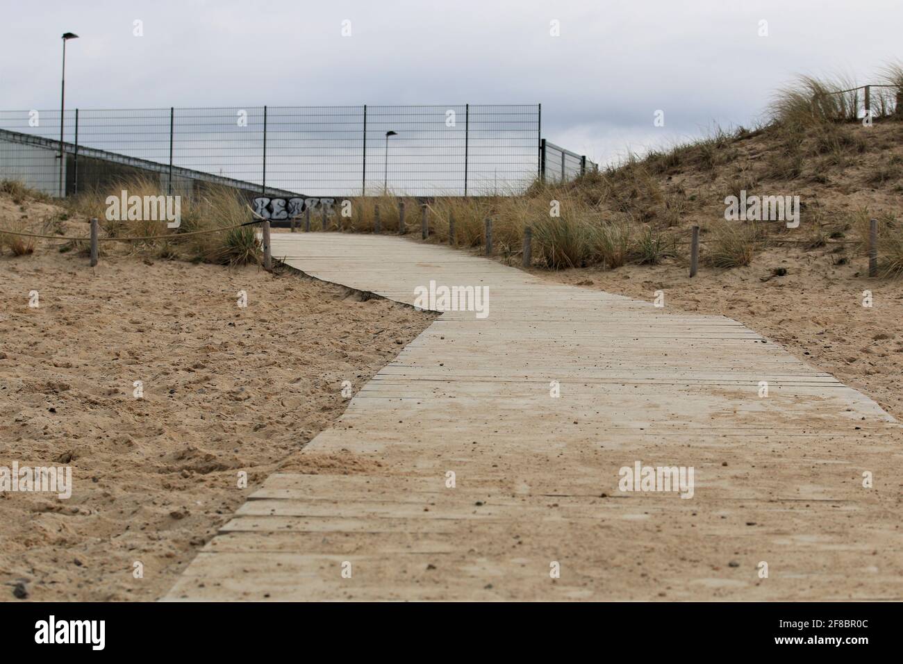 Beach with a wooden path as a closeup on a cold day Stock Photo