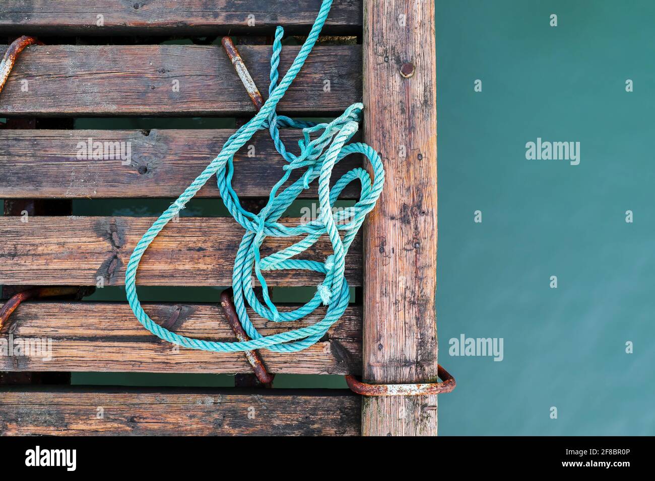 Wooden pier with blue sea. Wood floor or terrace beside the blue crystal clear water and a rope. Stock Photo