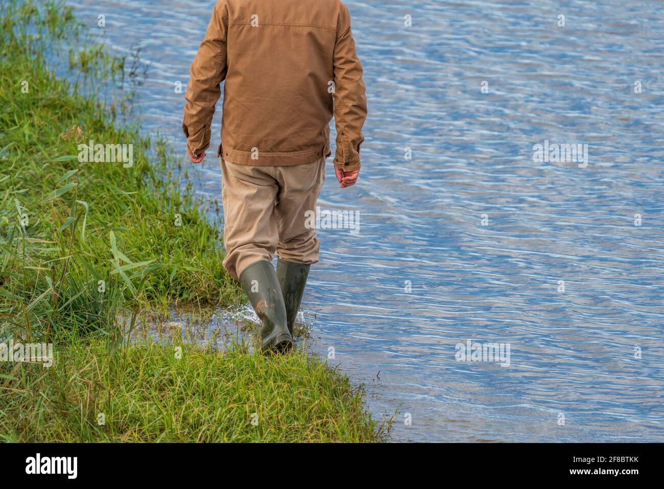 Unrecognizable person walking near flooded road edge Stock Photo