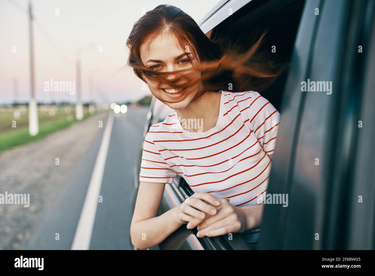 woman in striped t-shirt red hair car window salon model Stock Photo