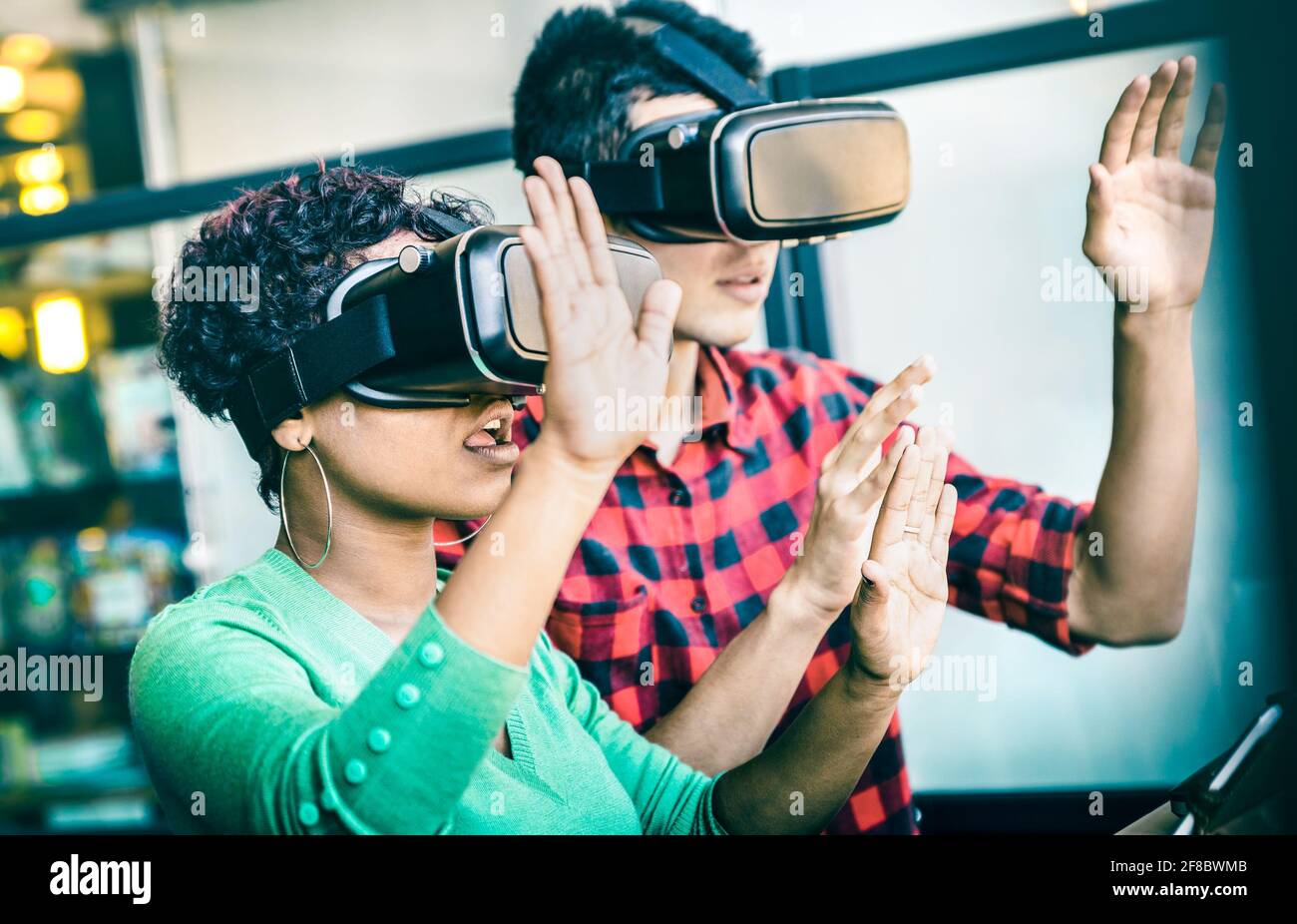 Multiracial couple in love going beyond racial diversity through virtual reality glasses - Young people having fun using new technology Stock Photo