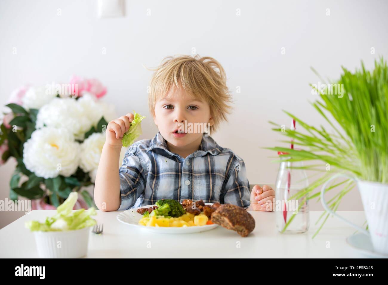 Little toddler child, blond boy, eating boiled vegetables, broccoli