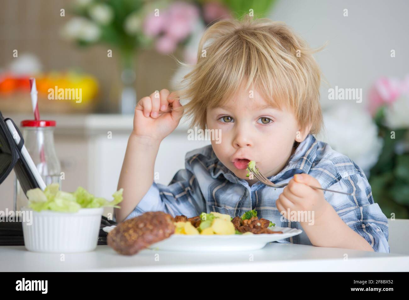Little toddler child, blond boy, eating boiled vegetables, broccoli