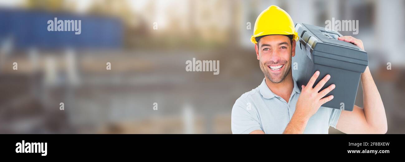 Smilling caucasian male construction worker holding tool box , construction site background Stock Photo