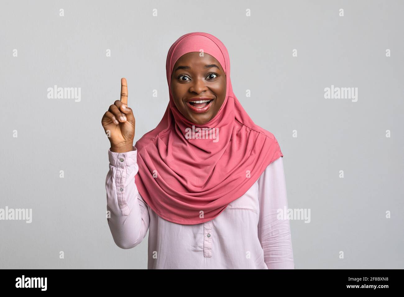Inspired black lady pointing finger up, grey background Stock Photo