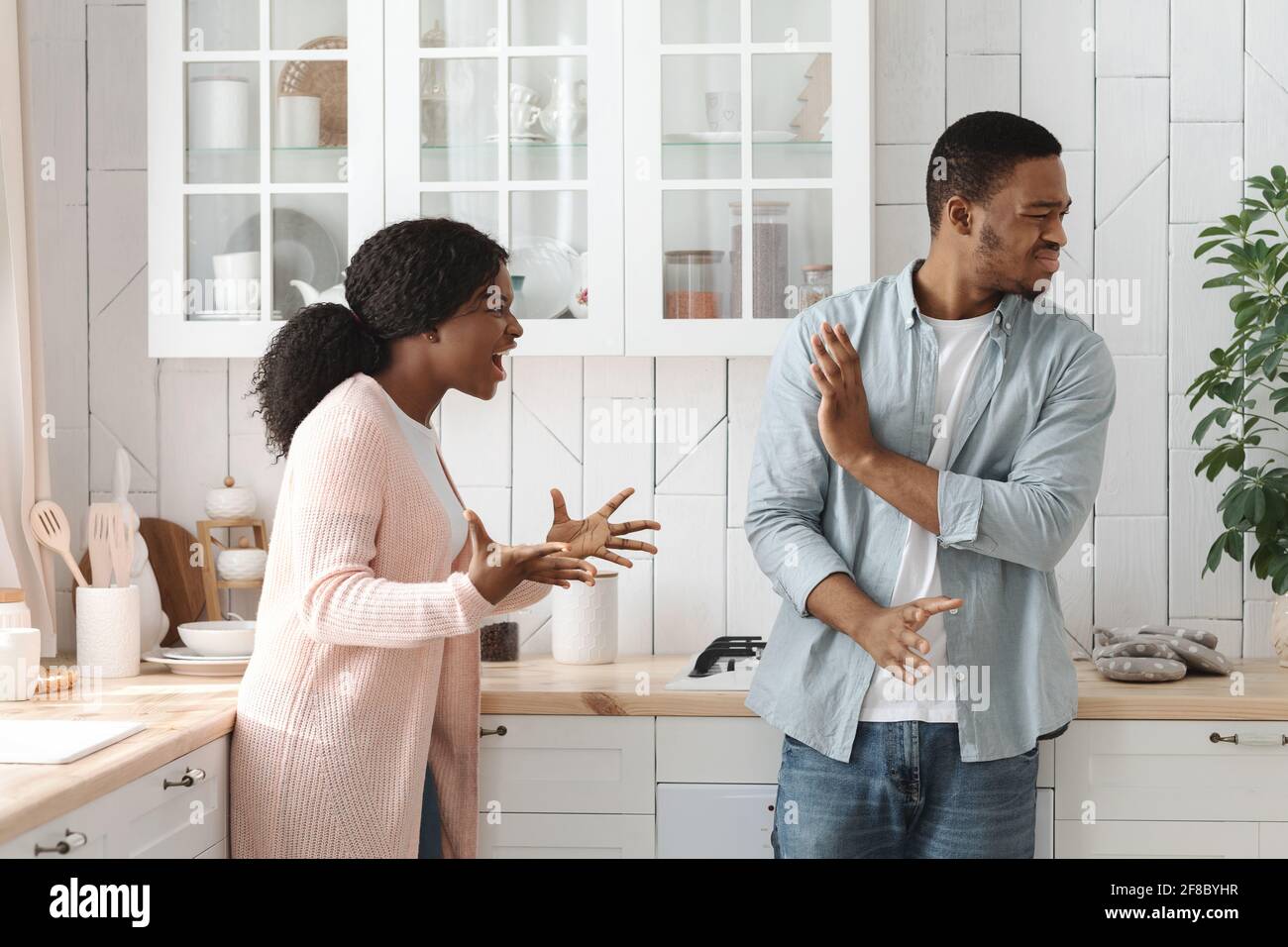 PMS Concept. Furious Young African American Woman Screaming At Husband In Kitchen Stock Photo
