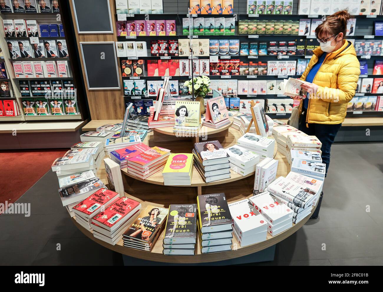 Leipzig, Germany. 13th Apr, 2021. A woman leafs through a book at a book  table in a Leipzig bookshop. The selection for the Leipzig Book Fair Prize  is more "female" than ever