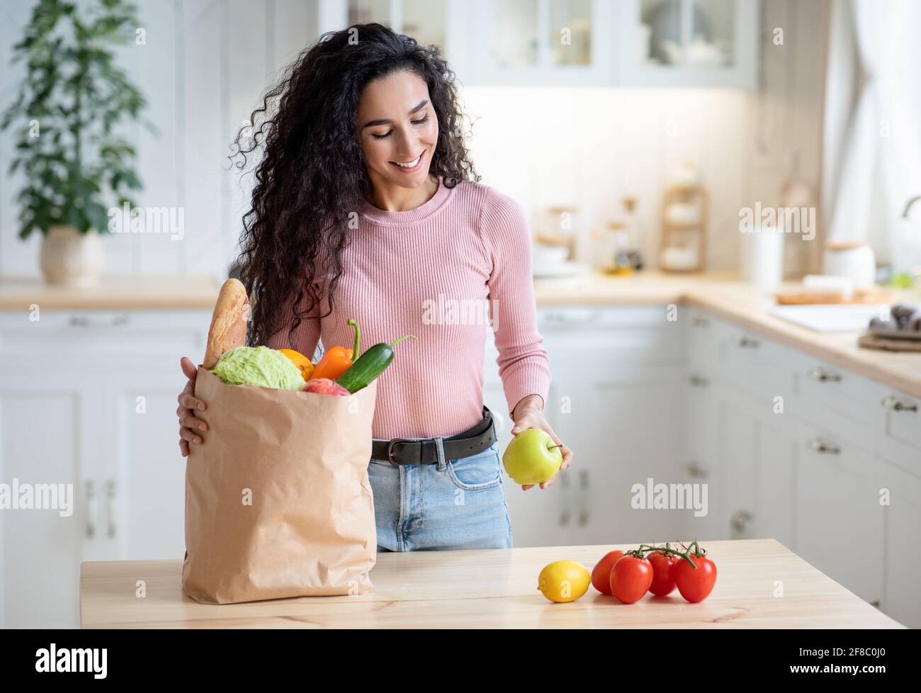 Happy Young Housewife Unpacking Groceries At Home After Shopping Stock Photo