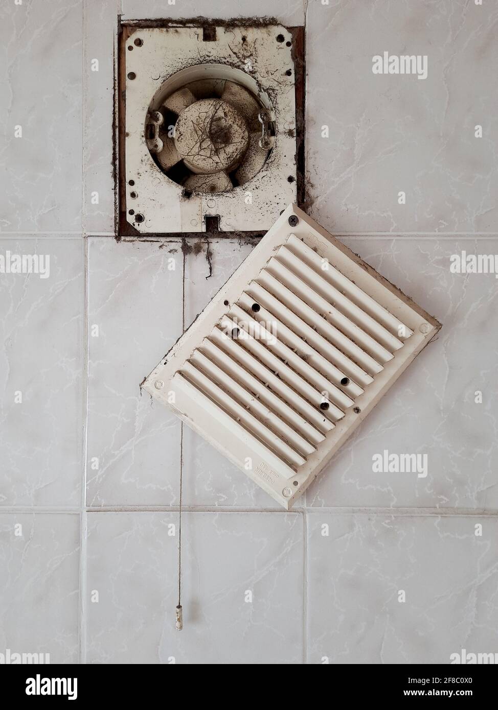 Dirty ventilation air grille with fan at home close up on white wall