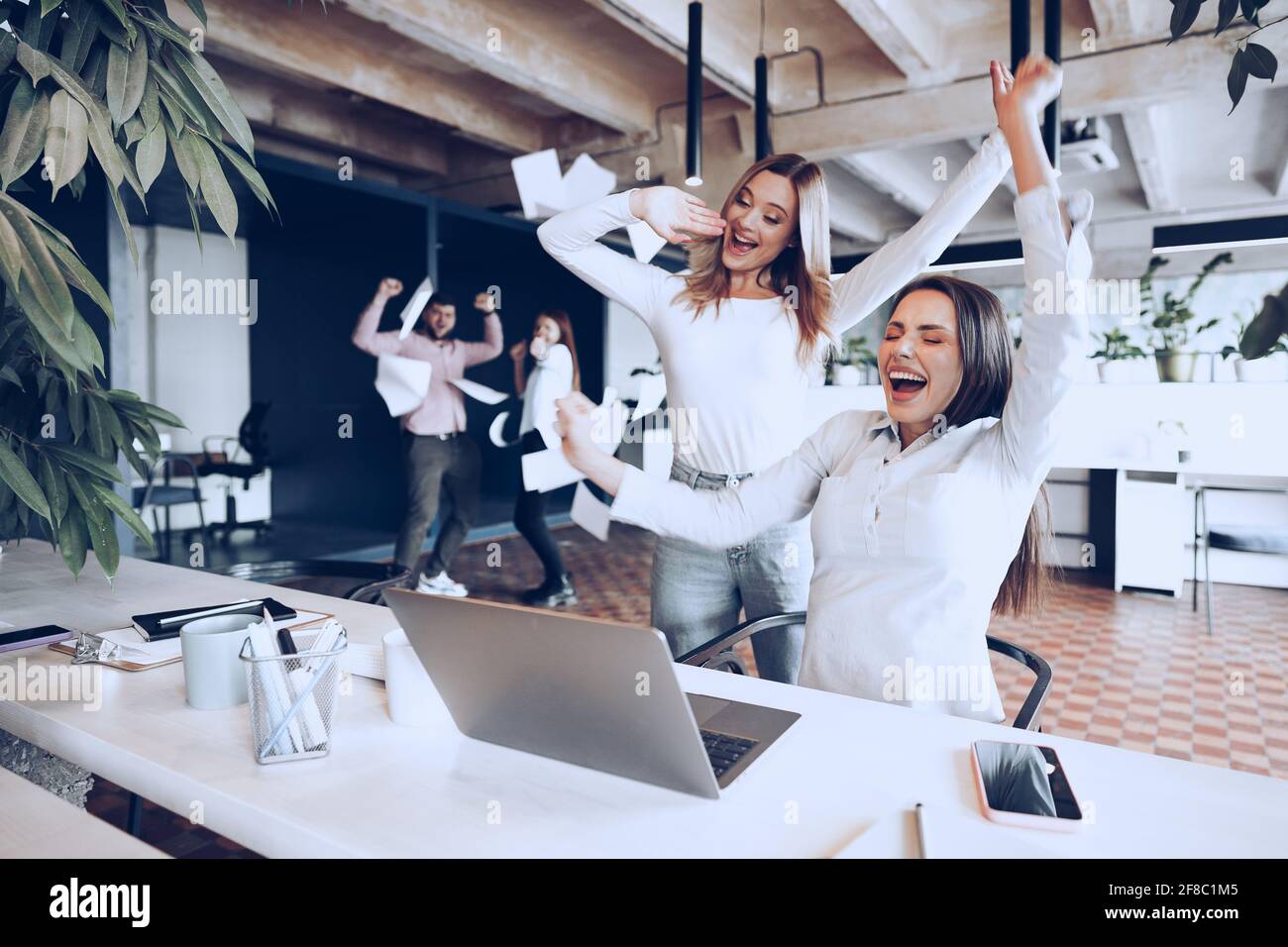 Two young happy businesswomen celebrating project success in office ...