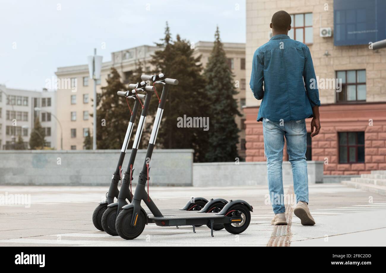 Black guy walking near rental motorized kick scooters Stock Photo Alamy